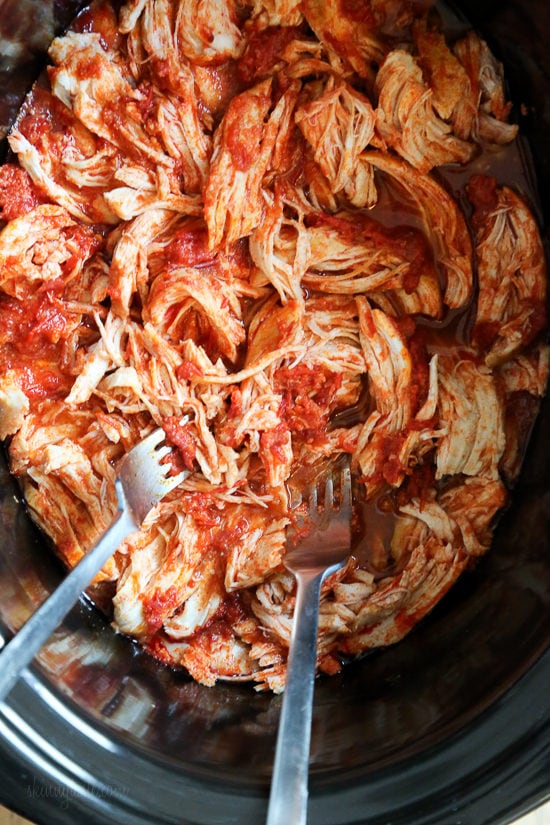 An easy harissa chicken recipe made in the slow cooker or Instant Pot, made with just 5 ingredients! Perfect for bowls, meal prep, and more. Overhead view of shredded spicy harissa chicken inside the slow cooker.