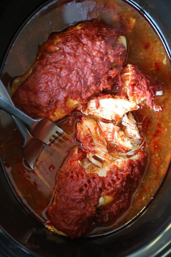 An easy harissa chicken recipe made in the slow cooker or Instant Pot, made with just 5 ingredients! Perfect for bowls, meal prep, and more. Overhead view of partially shredded harissa chicken inside the slow cooker.