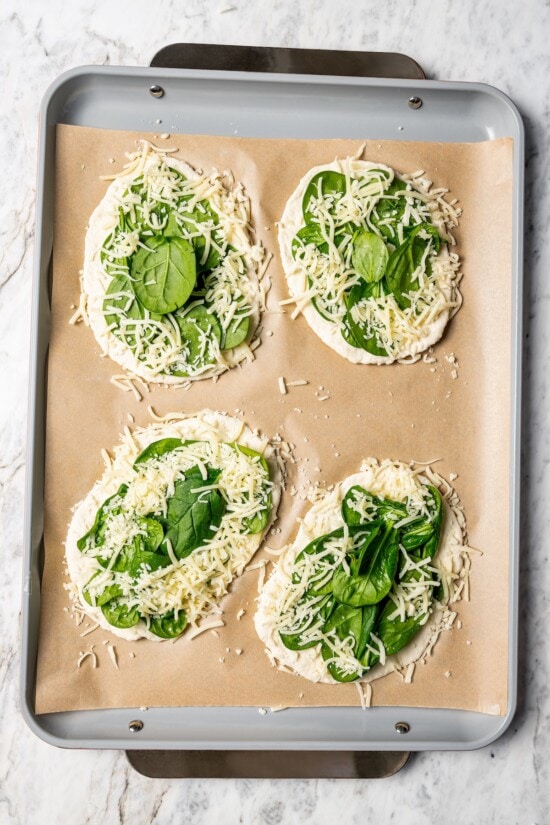 This easy breakfast pizza features a crispy yogurt crust topped with eggs, cheese, spinach and bacon for a savory protein-packed meal. Breakfast pizzas topped with mozzarella and spinach.