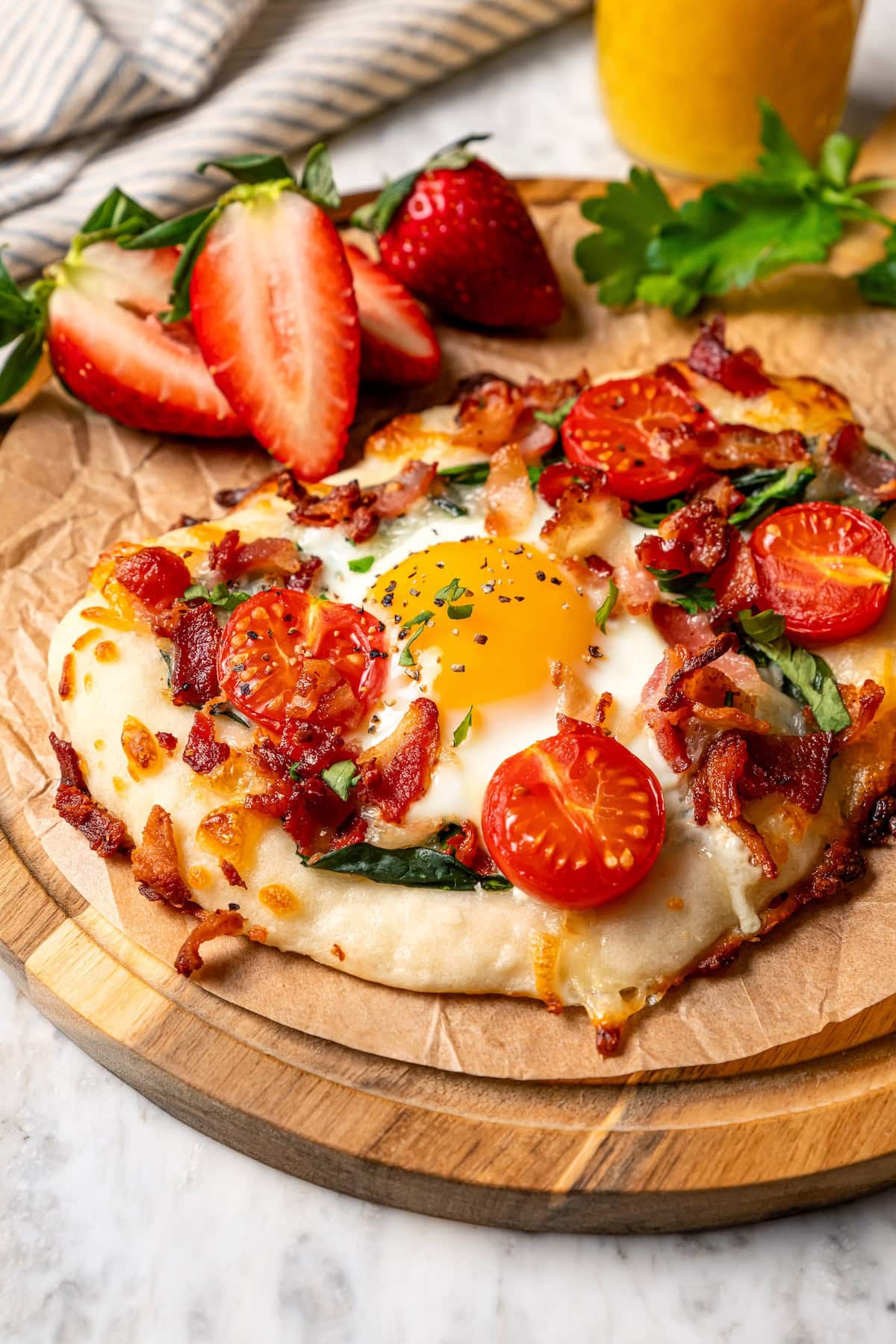 This easy breakfast pizza features a crispy yogurt crust topped with eggs, cheese, spinach and bacon for a savory protein-packed meal. Breakfast pizza topped with egg, tomatoes, spinach, and bacon.