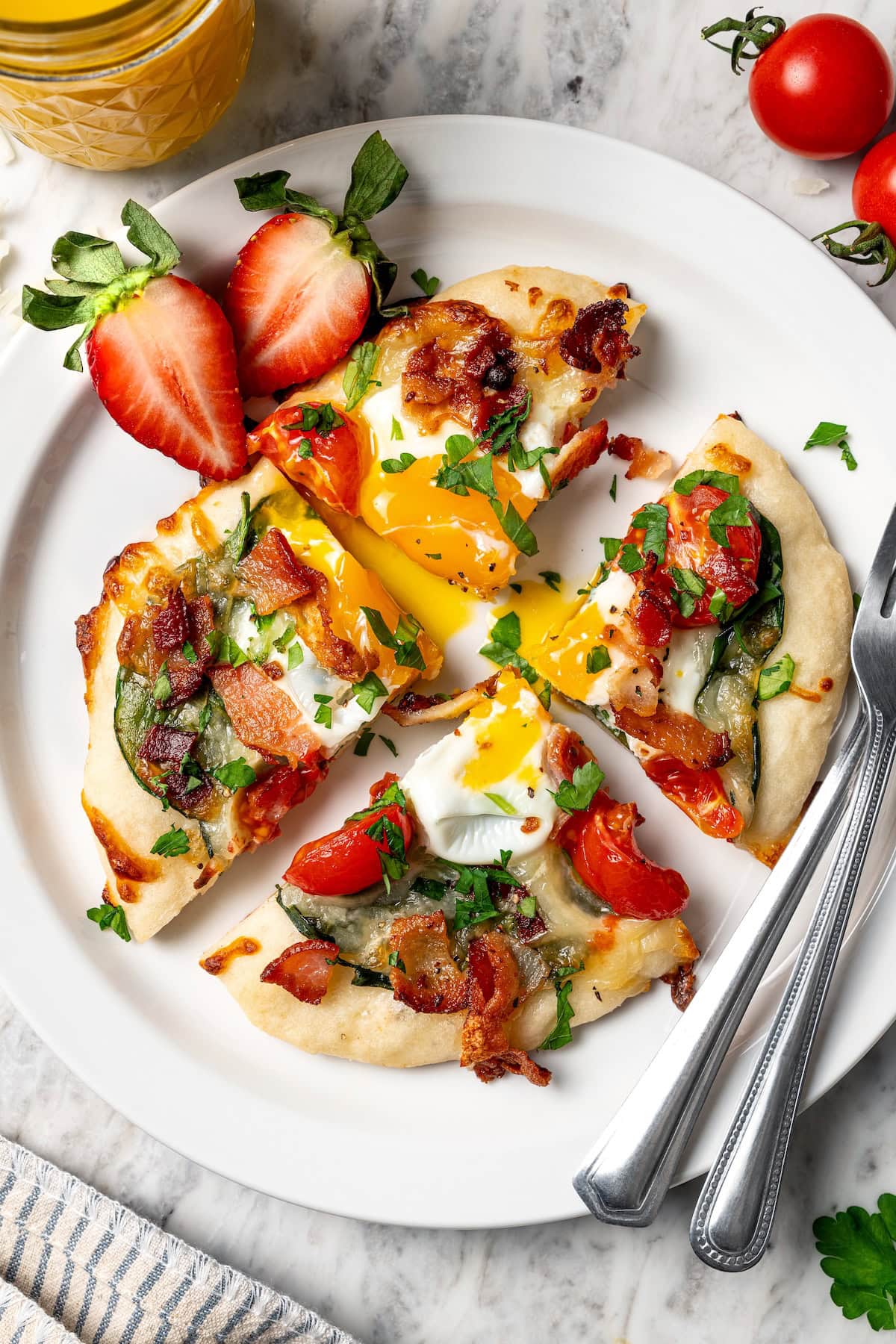 This easy breakfast pizza features a crispy yogurt crust topped with eggs, cheese, spinach and bacon for a savory protein-packed meal. Breakfast pizza on plate with runny yolk, sliced into quarters.