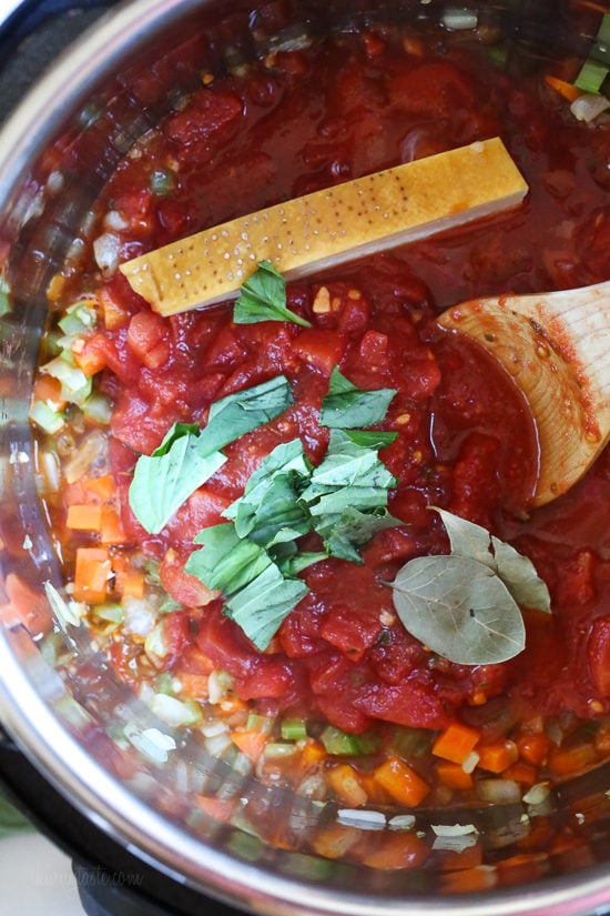 Instant Pot Turkey Meatball Soup is loaded with mini turkey meatball, zucchini, vegetables, and ditalini pasta. Hearty and healthy! A wooden spoon stirring tomatoes into veggies in the Instant Pot