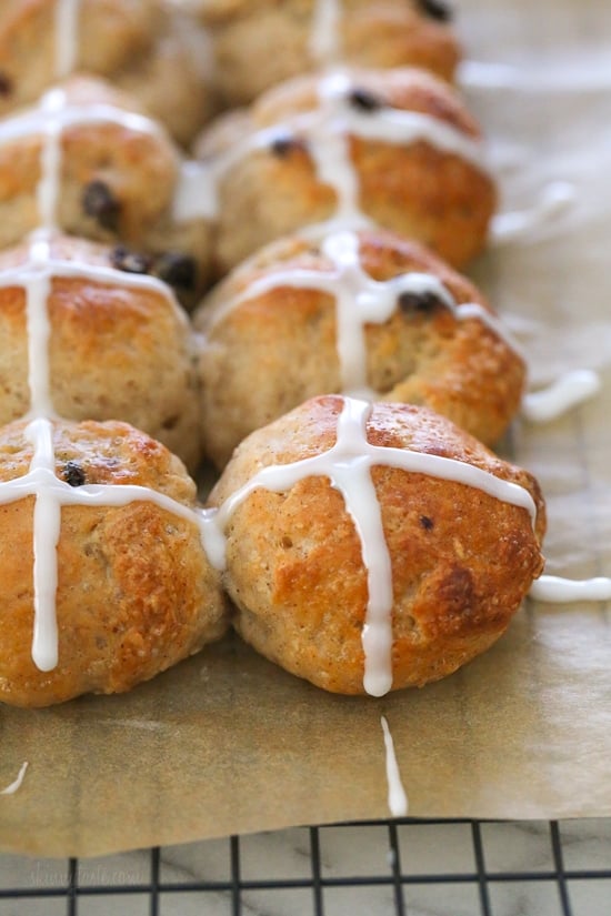 Make soft homemade hot cross buns without yeast, filled with spice, raisins, and finished with icing. Easy to bake in the oven or air fryer! Homemade hot cross buns topped with icing on a parchment-lined rack.