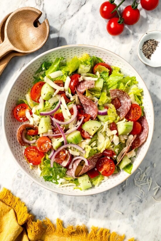 This easy Italian chopped salad pairs crisp romaine with salami, mozzarella, roasted red pepper, and veggies in red wine vinaigrette. Delish! Italian chopped salad in serving bowl.