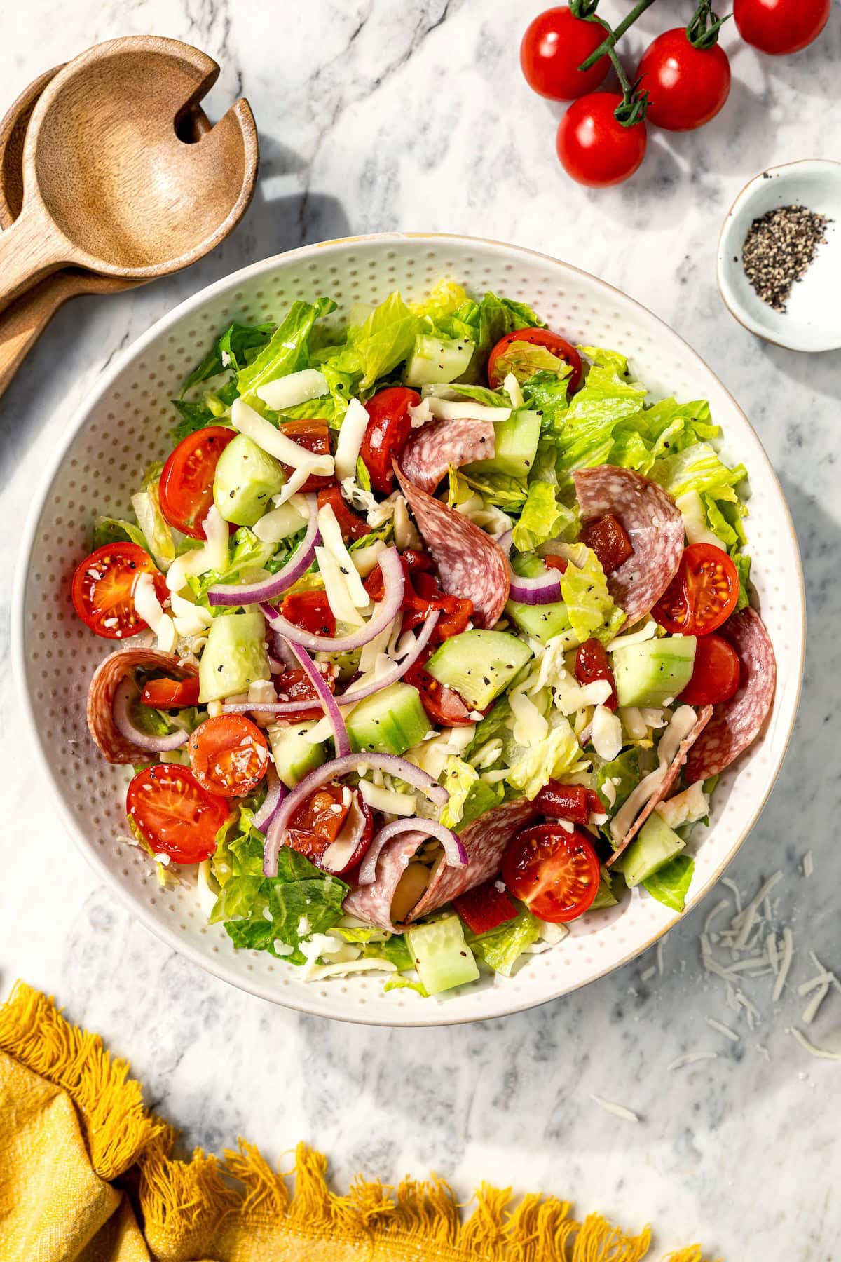 This easy Italian chopped salad pairs crisp romaine with salami, mozzarella, roasted red pepper, and veggies in red wine vinaigrette. Delish! Italian chopped salad in serving bowl.