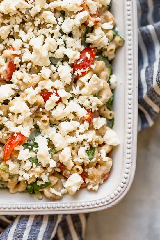 Greek Mac and Cheese, a healthy twist on a comfort food classic made in a creamy cheese sauce with whole wheat pasta, tomatoes, spinach, olives and Feta cheese.