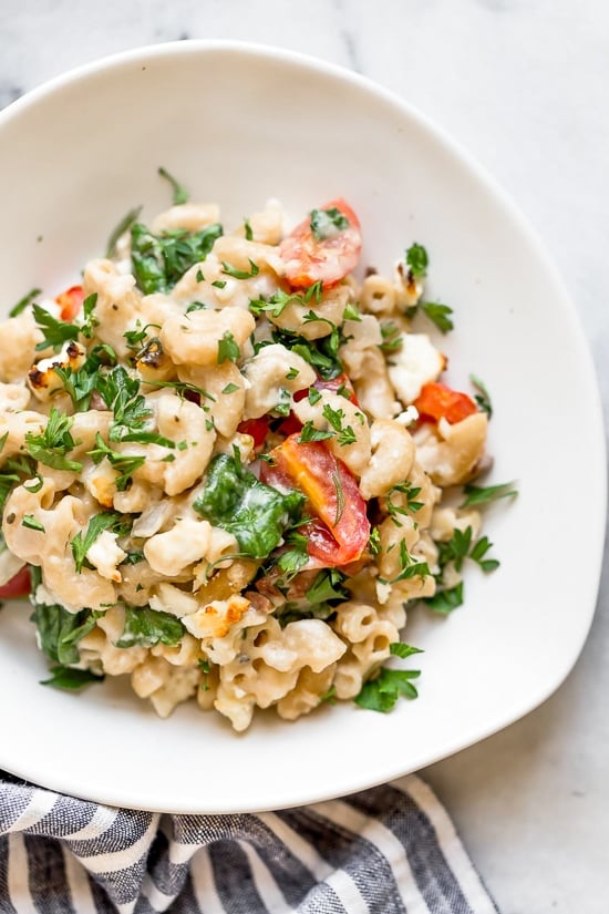 Greek Mac and Cheese, a healthy twist on a comfort food classic made in a creamy cheese sauce with whole wheat pasta, tomatoes, spinach, olives and Feta cheese.