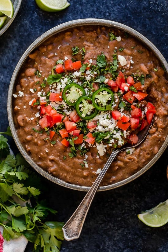 These Instant Pot Refried Beans are a simple, healthy, and fat-free version of the classic Mexican side dish. No oil or lard required! A bowl of refried beans topped with diced tomatoes and jalapeno