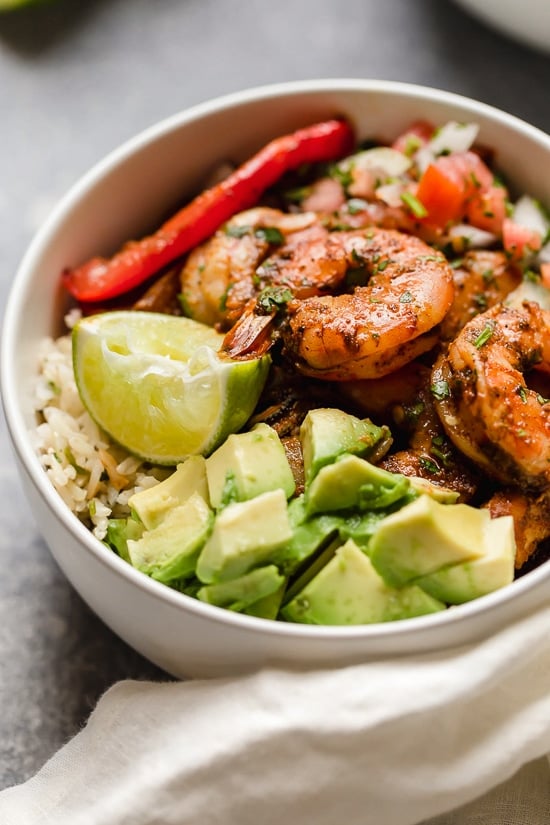 These Shrimp Fajita Bowls are a tasty and easy dinner that your whole family will love! Served over a bed of cilantro-lime rice with peppers and onions, avocado and salsa.