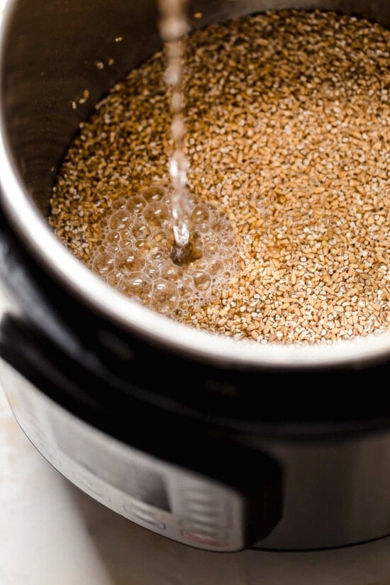 Instant Pot steel cut oats are so much faster than making them on the stove! Learn how to cook steel cut oats for a warm, hearty breakfast. Water being poured into an Instant Pot with steel cut oats