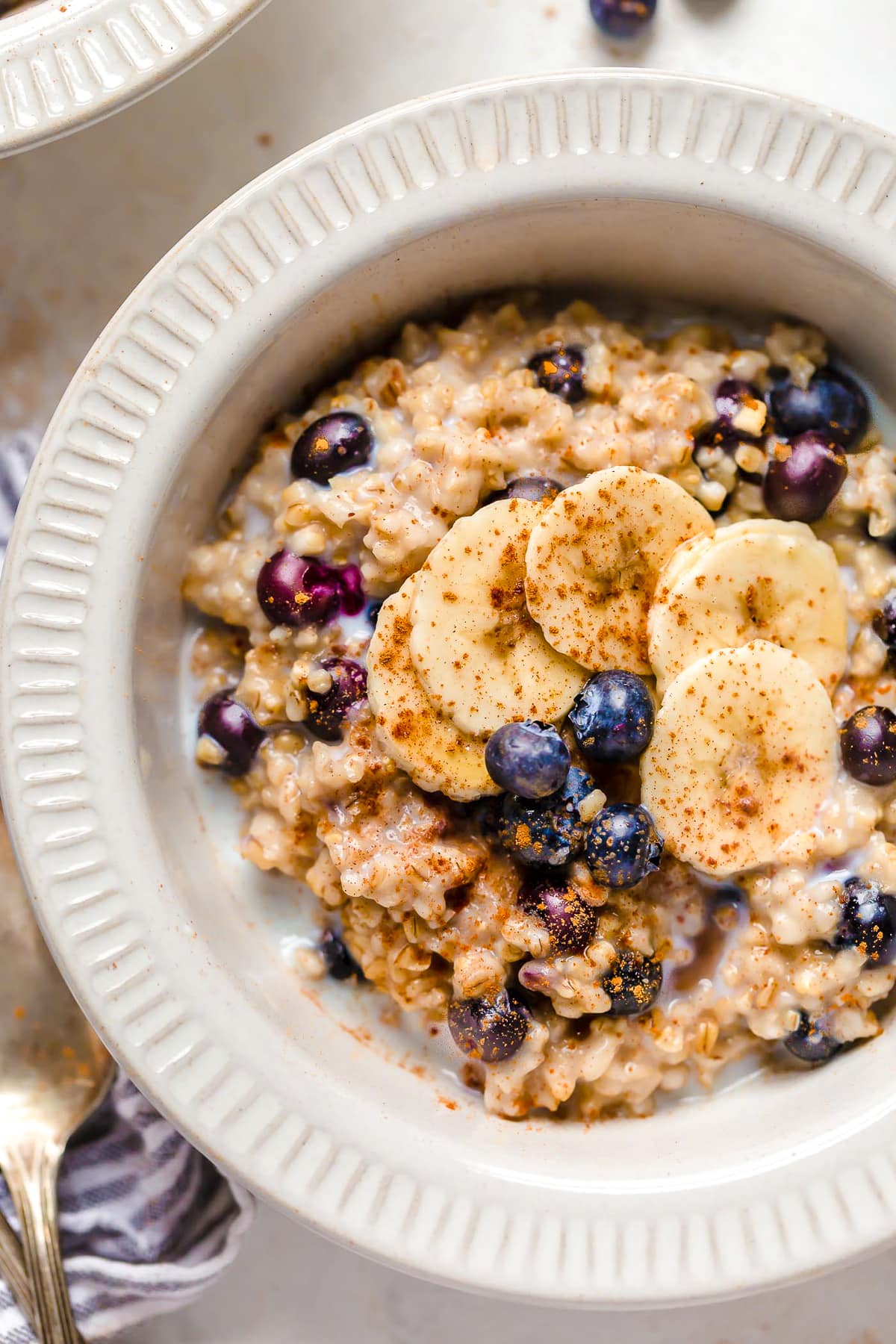 Instant Pot steel cut oats are so much faster than making them on the stove! Learn how to cook steel cut oats for a warm, hearty breakfast. A bowl of steel cut oats topped with blueberries and bananas.