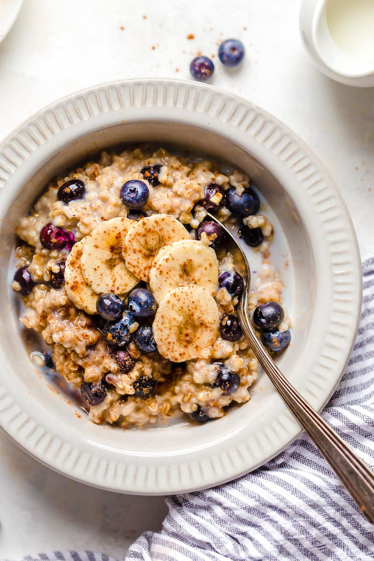Instant Pot steel cut oats are so much faster than making them on the stove! Learn how to cook steel cut oats for a warm, hearty breakfast. A spoon in a bowl of oats with blueberries and bananas.