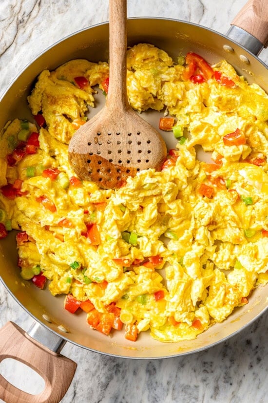 These easy freezer breakfast burritos are a delicious, protein-packed way to start the day with scrambled eggs, veggies, bacon and cheese. Scrambled eggs and veggies in pan