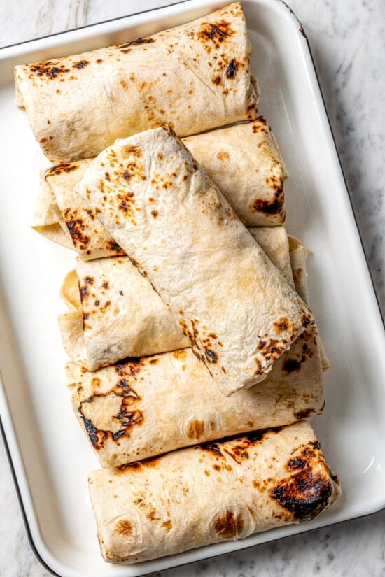 These easy freezer breakfast burritos are a delicious, protein-packed way to start the day with scrambled eggs, veggies, bacon and cheese. Breakfast burritos in casserole dish
