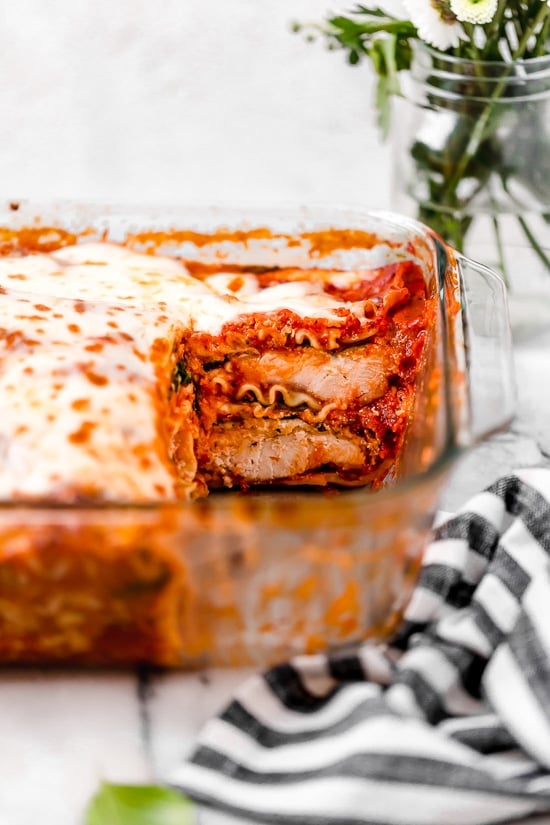This easy Chicken Parmesan Lasagna is a combination of two classic dishes. It's the perfect family-friendly dish to feed a large crowd! A casserole of chicken parmesan lasagna with a piece missing