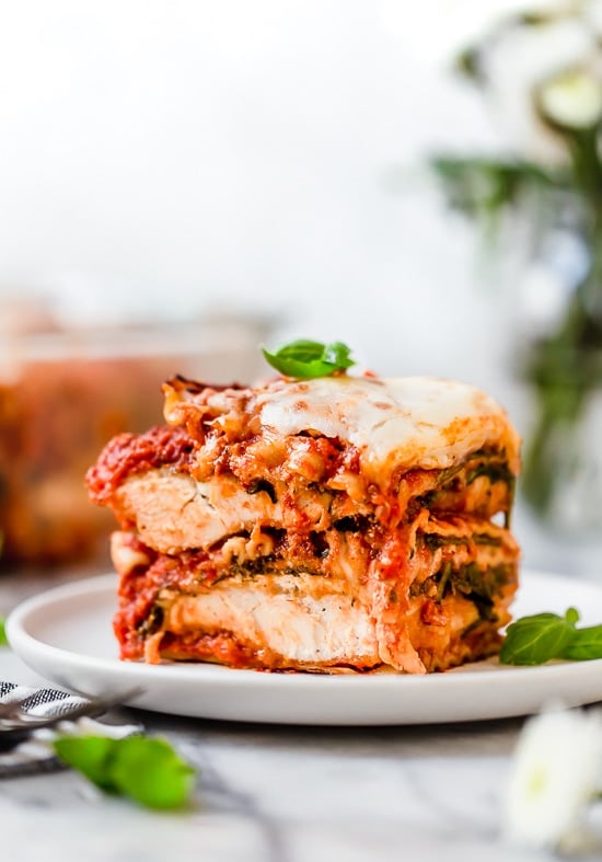 This easy Chicken Parmesan Lasagna is a combination of two classic dishes. It's the perfect family-friendly dish to feed a large crowd! A slice of chicken parmesan lasagna on a plate