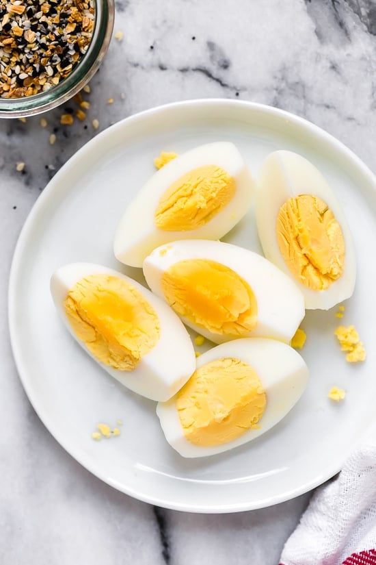This easy foolproof stove top method for making hard boiled eggs gives you PERFECT results every time. The best way to hard boil eggs! Overhead view of quartered hard boiled eggs on plate