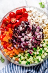 A bowl of olives, cucumbers, feta, tomatoes and bell peppers