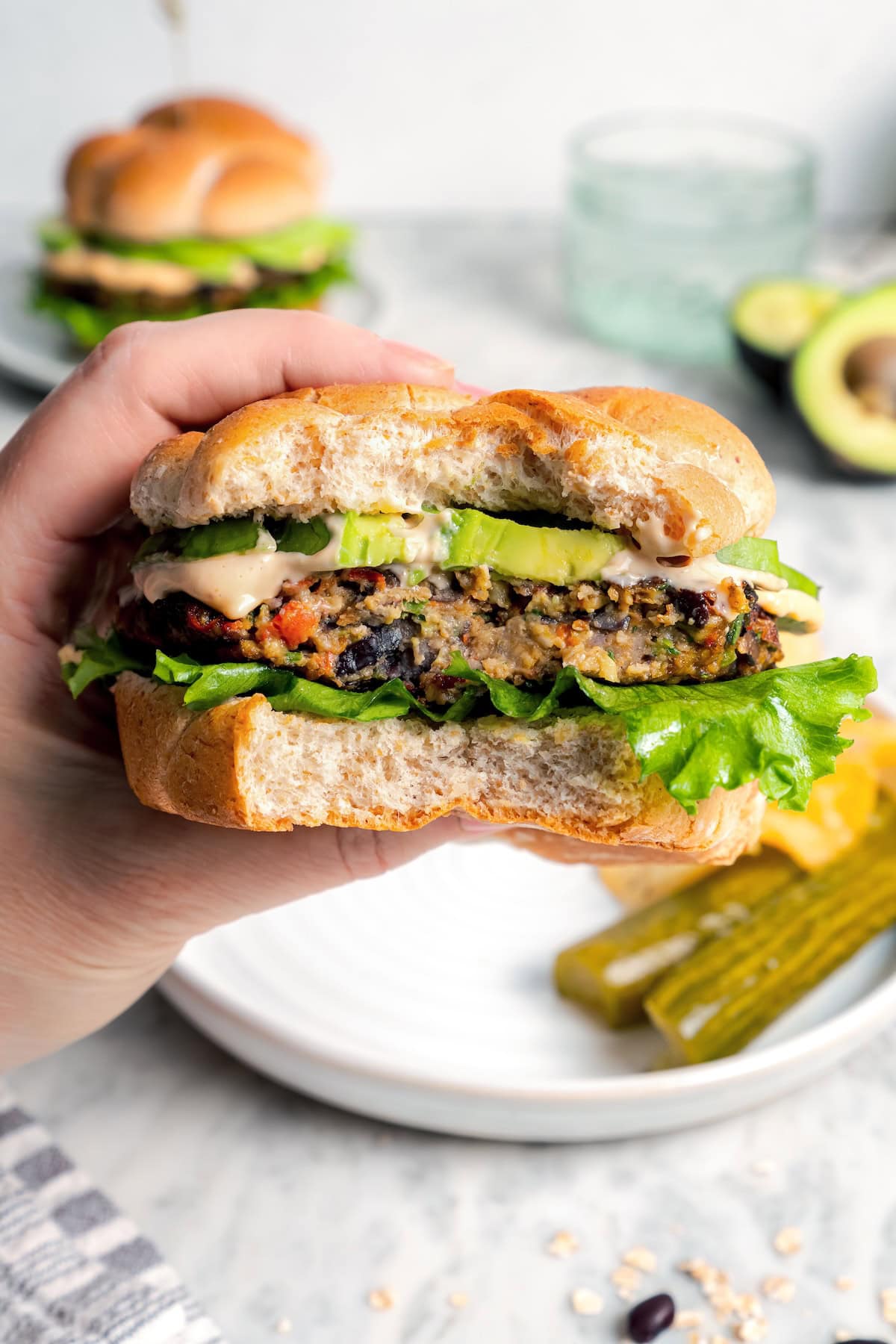 These black bean burgers are flavorful, satisfying and easy to make ahead. With a smoky chipotle mayo and avocado on top, they're delicious! Hand holding veggie burger with bite taken out