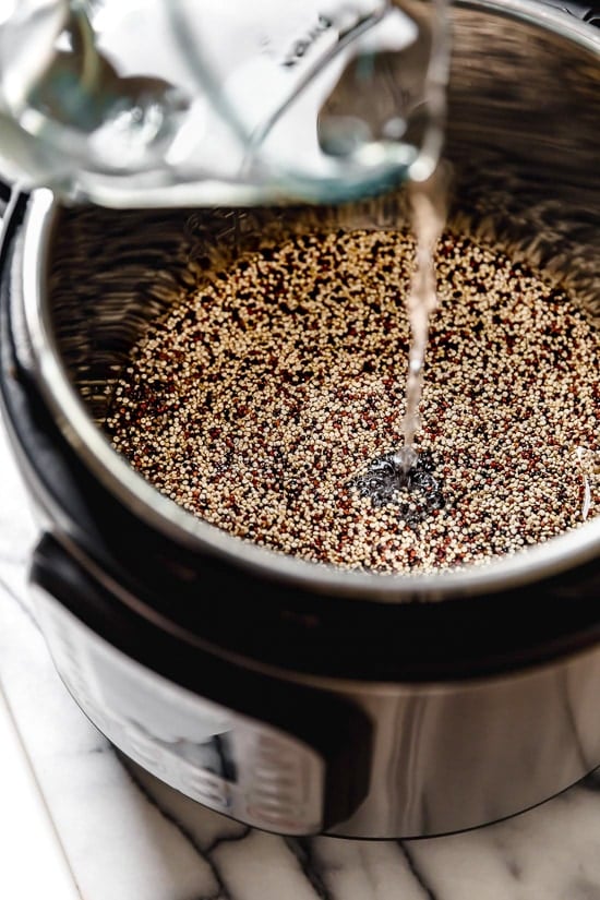 Learn how to cook perfect, fluffy Instant Pot quinoa! This hands-free method makes tender quinoa that's great in salads, bowls, and more. Water is added to an Instant Pot filled with uncooked quinoa.