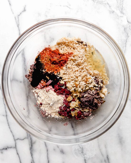 Made with beans and grains, this veggie burger recipe is hearty and satisfying, and the seasonings make it a standout. Perfect for freezing! Ingredients for veggie burgers in glass bowl.