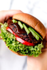 Hands holding veggie burger on bun.