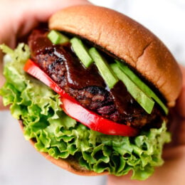 Hands holding veggie burger on bun.