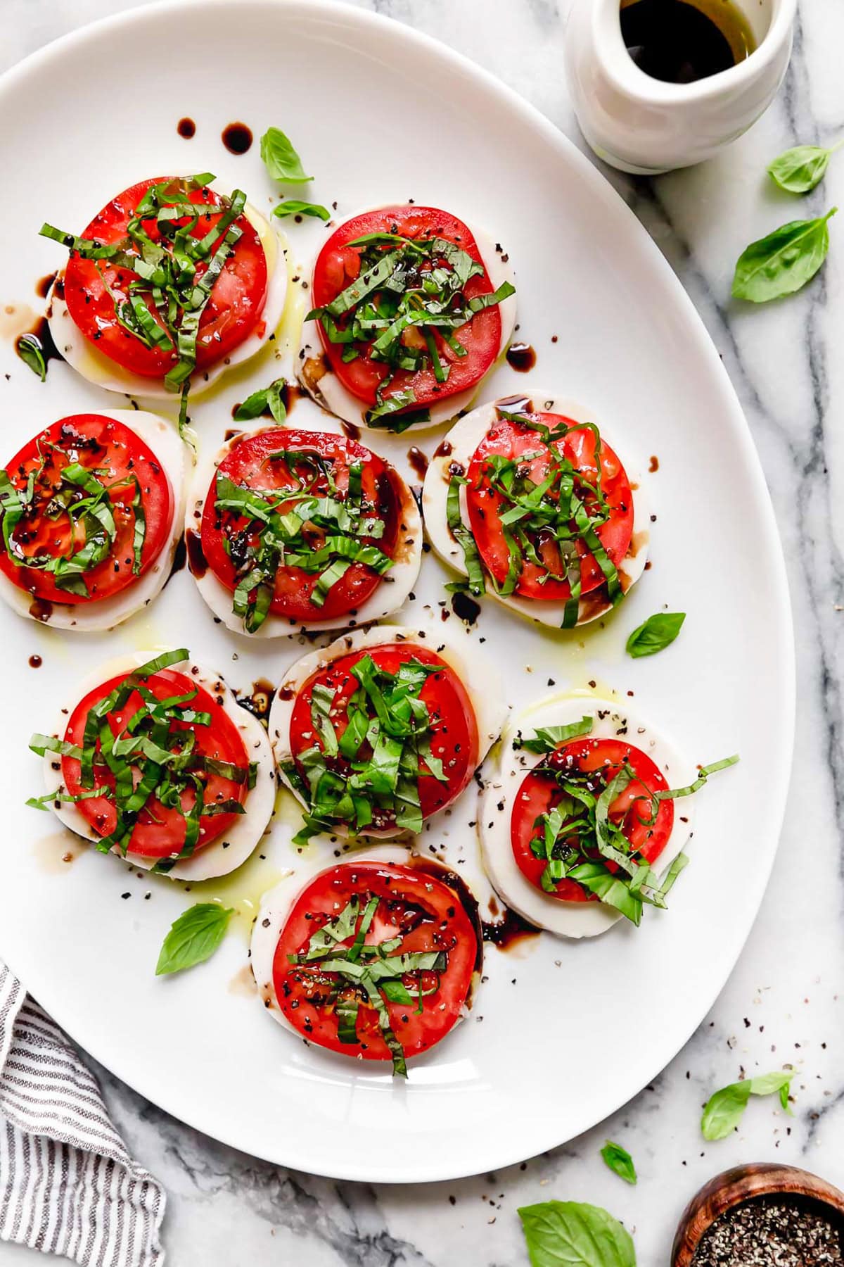 Caprese salad is a simple summer salad with fresh mozzarella, thick slices of juicy tomatoes, basil and a splash of balsamic vinegar. So easy! Overhead view of Italian Caprese salad on platter
