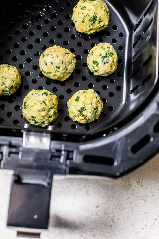This easy air fryer falafel recipe is made quicker and lighter with canned chickpeas, and no deep frying! Perfect for serving with hummus. Overhead view of falafel balls inside the air fryer basket.