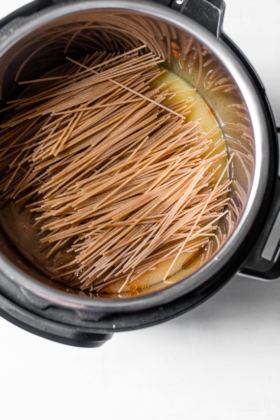 This healthy Instant Pot spaghetti and meatballs is made in one pot with juicy turkey meatballs, homemade marinara and whole wheat pasta. Spaghetti added to broth in instant pot.