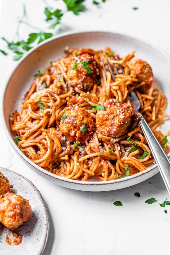 This healthy Instant Pot spaghetti and meatballs is made in one pot with juicy turkey meatballs, homemade marinara and whole wheat pasta. Bowl of Instant Pot spaghetti and turkey meatballs with fork.