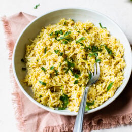 Rice pilaf in bowl with parsley for garnish.