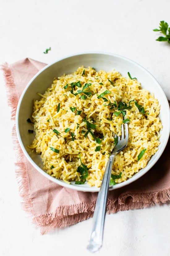 This homemade Rice-a-Roni style rice pilaf is made with toasted pasta, brown rice, and broth for an easy, buttery, family-friendly side dish. Rice pilaf in bowl with parsley for garnish.