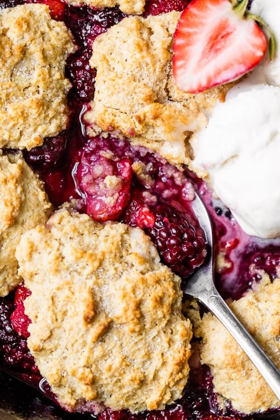Skillet Mixed Berry Buttermilk Cobbler is made with blackberries, raspberries, and strawberries covered with a delicious biscuit topping and baked in a cast iron skillet.