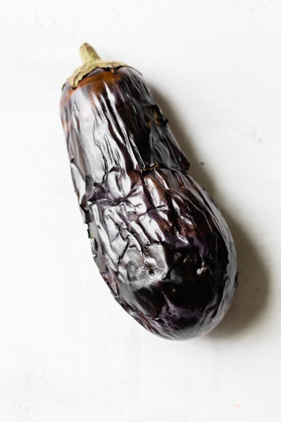 This authentic baba ganoush recipe is smoky, smooth, lemony and garlicky. It's a healthy dip that's easy to make and so delicious! Charred eggplant on countertop.
