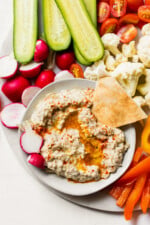 Dipping pita triangle in bowl of baba ganoush.