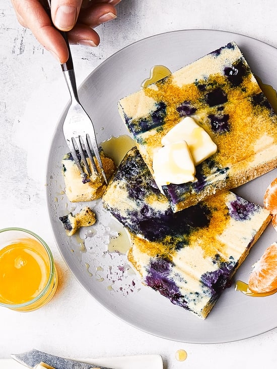 This easy sheet pan pancakes recipe is essentially a giant, fluffy pancake baked in the oven. The most genius way of making pancakes! Lemon Blueberry Buttermilk Sheet Pan Pancakes on a plate with syrup.