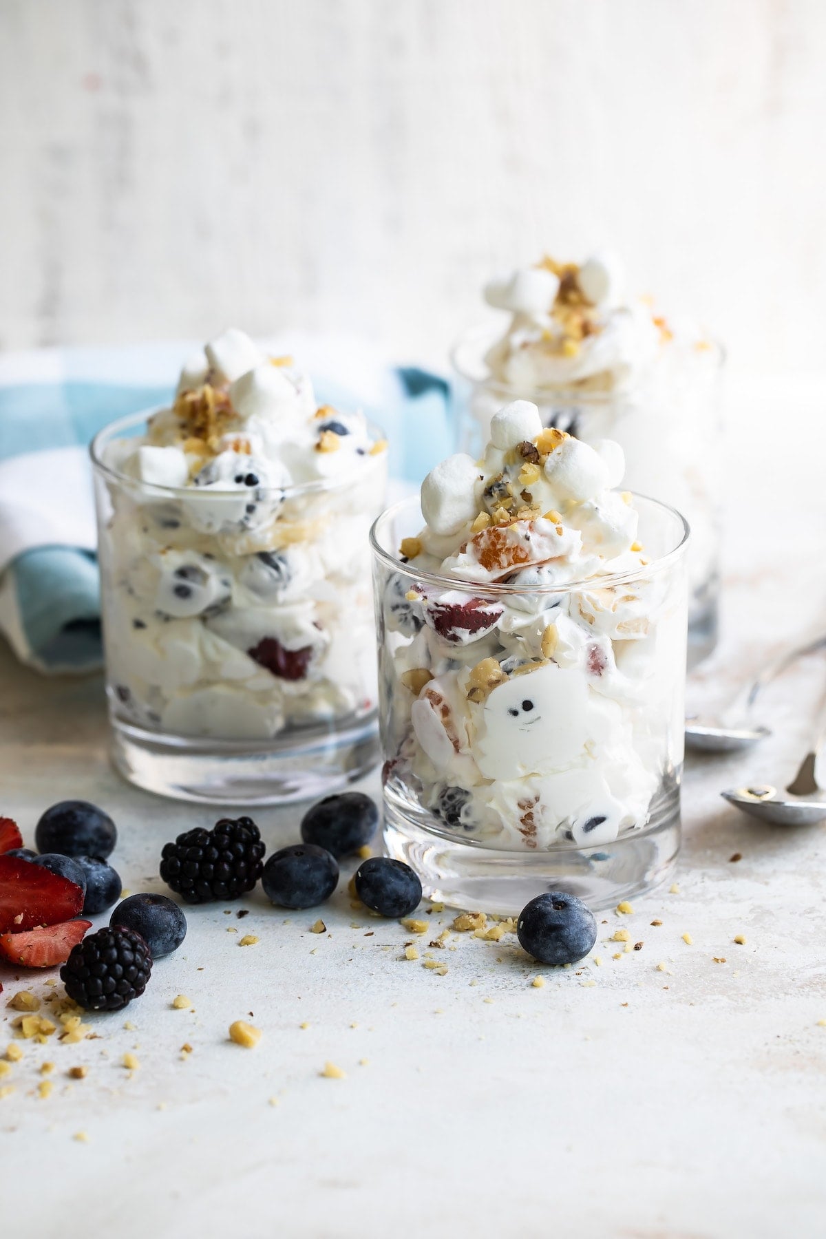 With a variety of fresh fruit, whipped cream, walnuts, and marshmallows, Ambrosia Fruit Salad is ready in minutes. A perfect summer dessert! Ambrosia Salad in 3 glass serving cups.