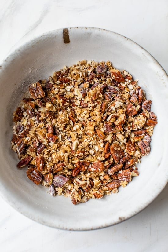 This lightened up Sweet Potato Casserole is made with roasted sweet potatoes and a praline topping for a crowd-pleasing Thanksgiving side! Praline nut and oat topping in bowl.