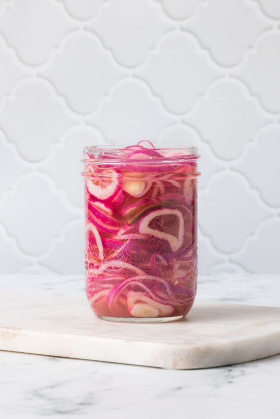 These easy pickled red onions are add a tangy, slightly sweet, and crunchy element to steaks, sandwiches, tacos, burrito bowls and more! red onions in mason jar