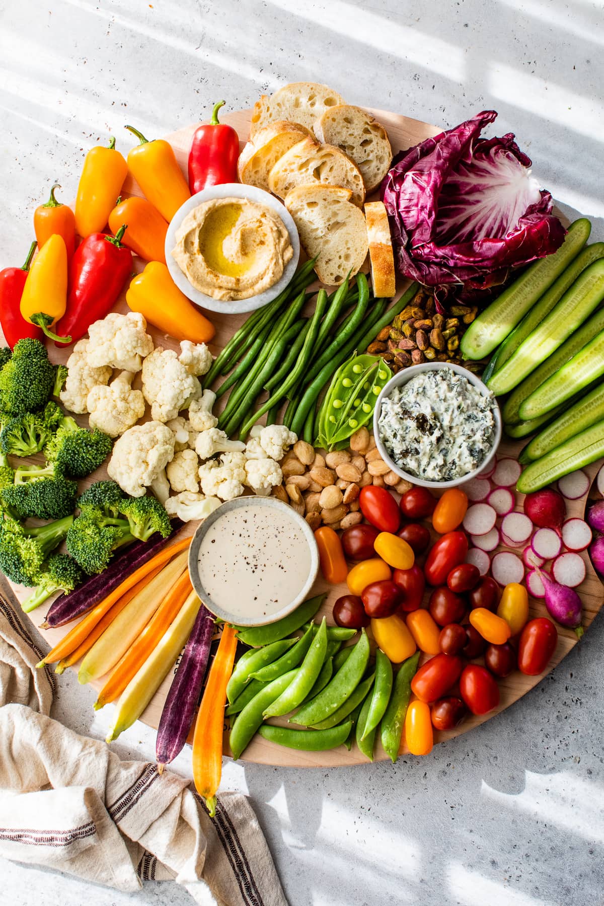 This modernized take on the veggie tray brings more visual appeal to the party staple. Like a vegetable charcuterie board with dips and more! Overhead view of veggie tray with 3 bowls of dip