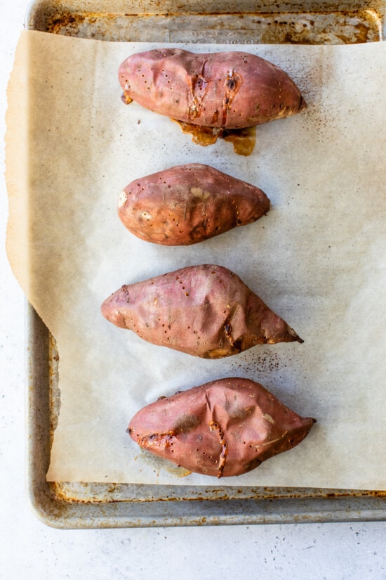 This lightened up Sweet Potato Casserole is made with roasted sweet potatoes and a praline topping for a crowd-pleasing Thanksgiving side! Baked sweet potatoes on parchment lined sheet pan.