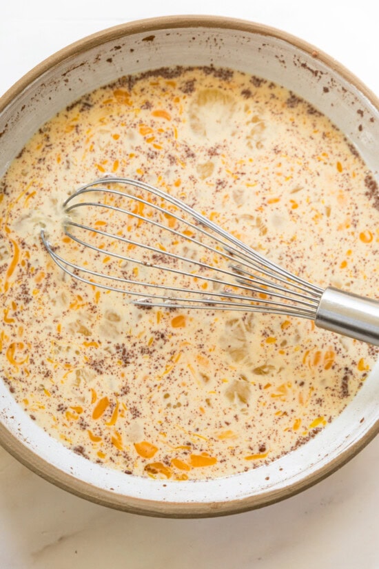 This overnight crème brûlée French toast bake is an easy make-ahead breakfast with fluffy challah, eggy custard, and only 15 minutes of prep! Egg custard in a bowl with a whisk.