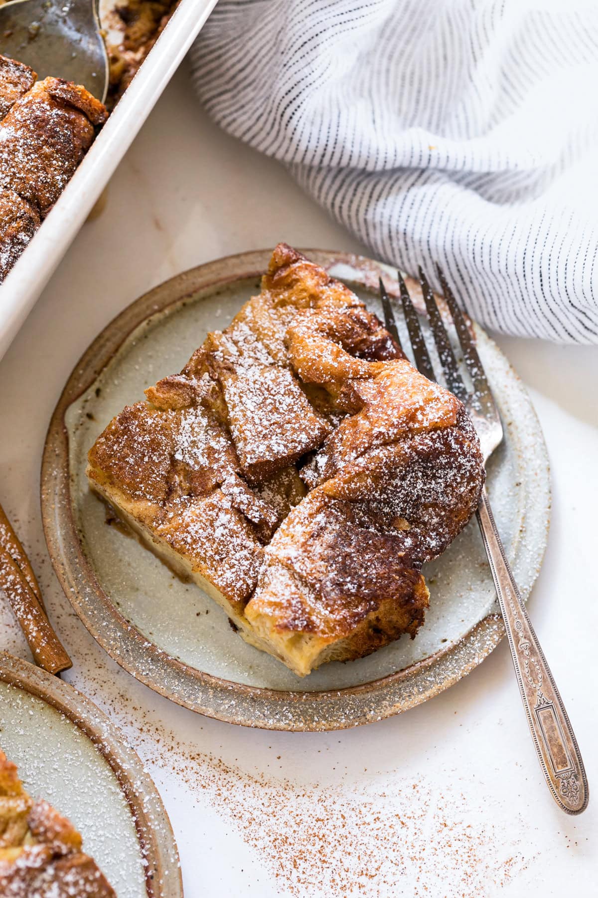 This overnight crème brûlée French toast bake is an easy make-ahead breakfast with fluffy challah, eggy custard, and only 15 minutes of prep! A slice of overnight creme brulee French toast on a plate with a fork.
