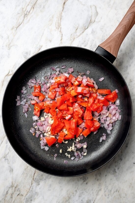 These vegan lentil tacos are easy to make, full of big Tex-Mex flavor and great for meal prep. Add your favorite toppings and dig in! Tomatoes added to skillet of red onions