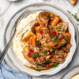 Bowl of mashed potatoes topped with slow cooker coq au vin.