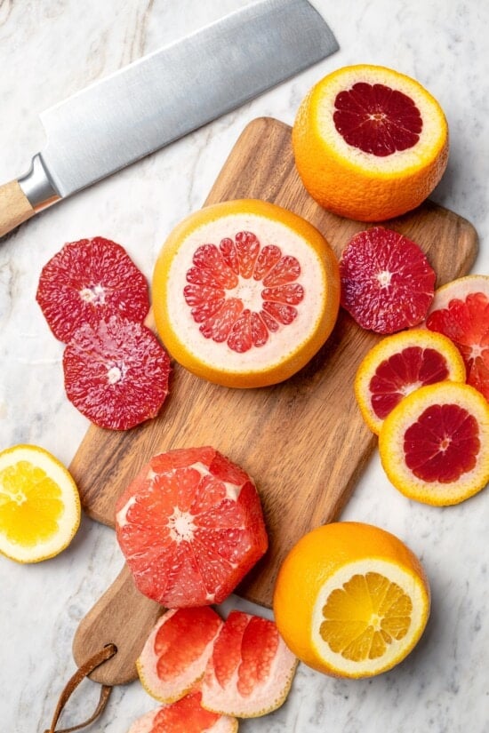 This Roasted Beet and Citrus Salad pairs tender beets with creamy goat cheese, citrus fruit and pistachios for a show-stopping holiday side! Sliced citrus fruit on cutting board set next to knife.