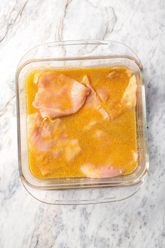 This Chick-Fil-A Egg White Grill copycat is made with juicy grilled chicken, fluffy egg whites and cheese for a hearty meal prep breakfast! Chicken breasts in pan of marinade.