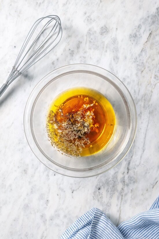 This homemade Greek salad dressing recipe blends simple pantry ingredients into a bright, zippy dressing you’ll want to pour on everything! Ingredients for Greek salad dressing in bowl.